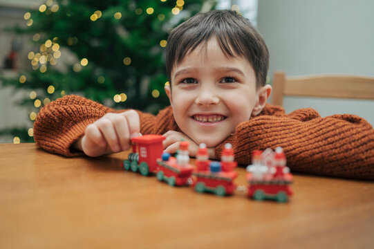 Smiling child playing with toy Christmas train at home holiday decor