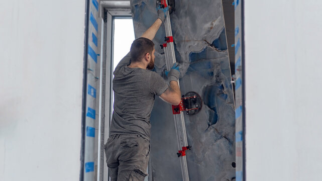 The master installs and holds large-format tiles. Professional tile work, tile installation, professional vacuum tile removal, huge XXL tiles, renovation, bathroom