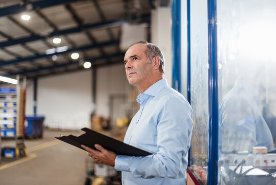 Business manager with clipboard in production hall indoors