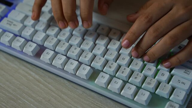 Hands typing on white mechanical keyboard, Close-up of hands typing on a white mechanical keyboard with pastel keycaps on a wooden desk