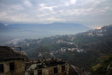 Obraz premium Scenic panorama of Gjirokaster town by misty evening, Albania
