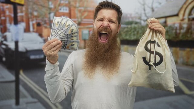 Bearded man holding cash fan and moneybag on bustling city street while sticking out tongue; excitement.