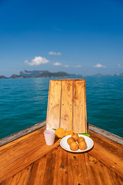 Wooden boat bow with traditional Thai offering on calm blue sea during boat trip to Ang Thong Marine National Park near Koh Samui, Thailand
