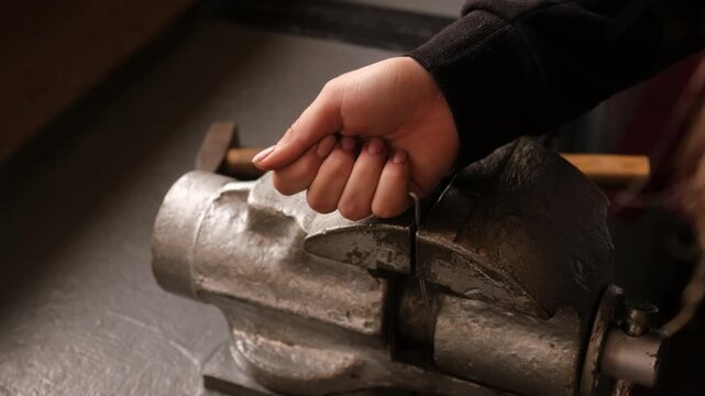 A person is working on a metal object with a hammer and a chisel