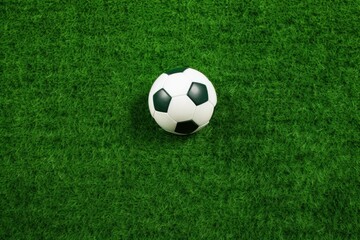 Fototapeta premium Classic soccer ball sits prominently on a vibrant green playing field, ready for action