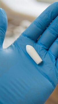Medical handling. Doctor wearing gloves holds white suppositories for vaginal or anal use. Candles for treatment of candidiasis, thrush, hemorrhoids, inflammation, fever. Close-up, interior of clinic