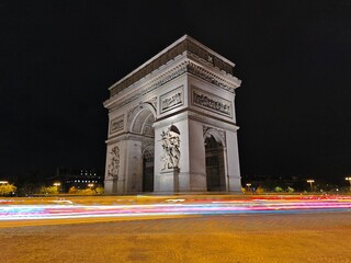 Fototapeta premium Long exposure night view of the Arc de Triomphe in Paris, majestic classical architecture and urban light trails