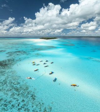 Aerial view of tropical sandbank, sea, tourist boats in turquoise water near Mnemba Island, Zanzibar, Tanzania. Crystal clear Indian Ocean, coral reef, white sandy beach, summer travel. Top drone view