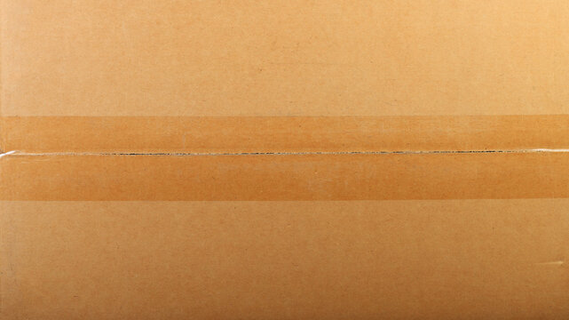 Texture of brown corrugated cardboard with clear adhesive tape, macro shot.
