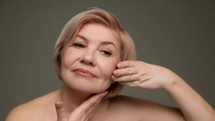 Selbstklebende Fototapeten Altes Krankenhaus Beelitz Mature woman supporting chin facial care concept. Concept of anti aging skincare branding, cosmetic promotion, dermatology marketing, natural beauty campaign for mature women.  © master1305