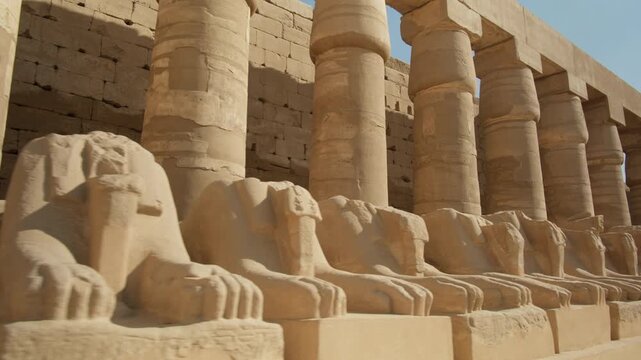 Ancient headless statues of ram-headed sphinxes along Bubastian columns in courtyard of Karnak Temple Complex,