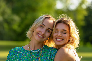 Fototapeta premium Two young women friends, portrait outside in nature on a sunny day of summer