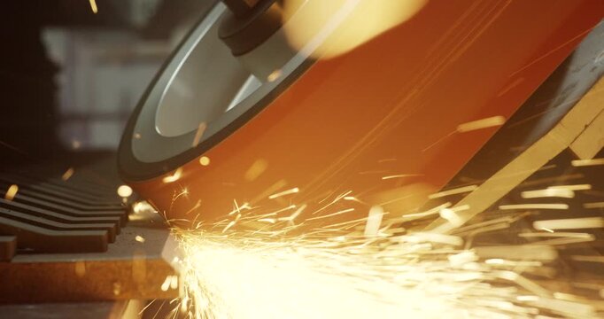 Close up of industrial beveling maschine wheel grinding metal surface with intense flying sparks