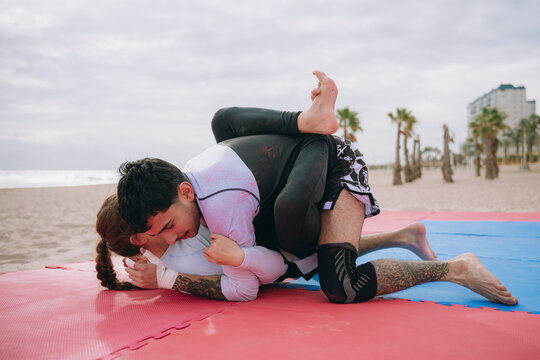 Athletes grappling on beach training brazilian jiu jitsu