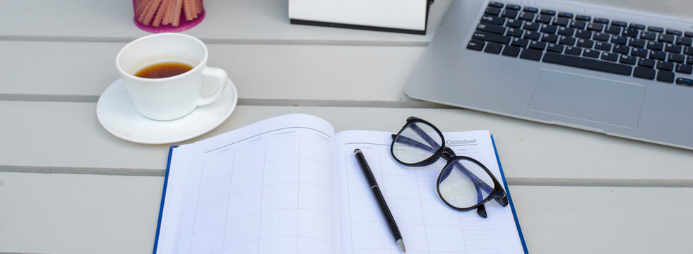 Business executive home office Desk Background concept. Business computer empty home office table with desktop laptop, calendar, notebook, clock, pencil, glasses and cup of coffee-banner image