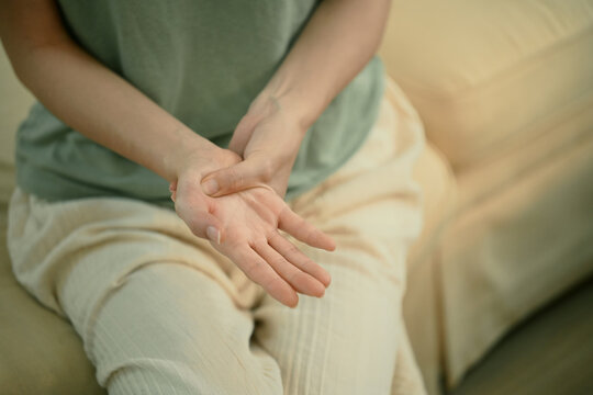 Closeup young woman hand pain her injury pain from cramp, trigger finger, touching massaging, ache joint