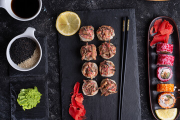 delishious sushi rolls   served  at black dish at black table. flat lay