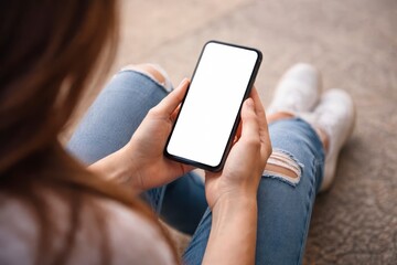 Woman sitting on floor holding smartphone with blank screen in hands  using mobile phone JPG image