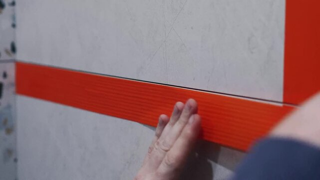 Master tiler tapes tile seams before epoxy grouting. preparatory work, professional tile work, grouting seams, epoxy grout, grouting, bathroom renovation, tile installation