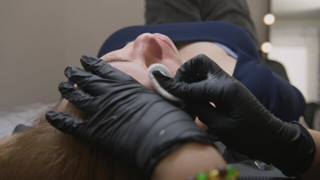 Professional microblading session with tattoo needle machine for permanent eyebrow makeup on woman in beauty salon. Detailed hair strokes technique, perfect brow transformation 