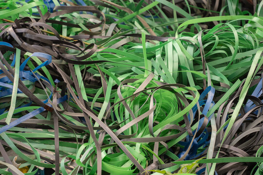 Tangled pile of green and black plastic packing straps at a recycling site. Industrial waste management and material recycling concept.