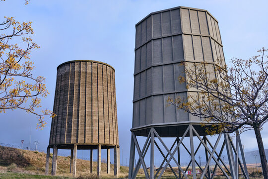 View of two weathered, cylindrical towers, one smooth and one segmented, stand as relics against a pale sky, in Puertollano, Castile-La Mancha, Spain.
