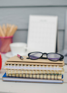 Desk for student education concept. Calendar, Laptop, Pencils, book, note pad placed on School table for student work online at home-vertical image.