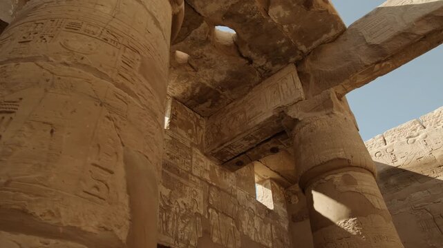 Walking and looking up at massive stone columns with capitals and architrave of Vestibule of Thutmose III at Karnak Temple in Luxor, Egypt