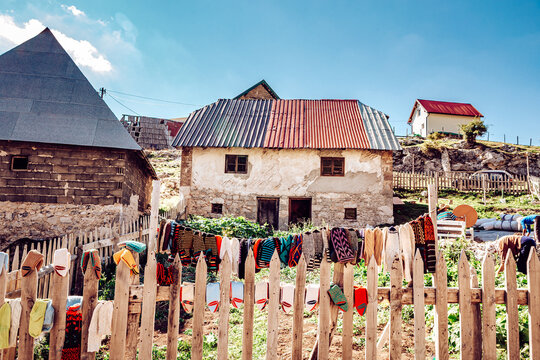 View of rustic charm unfolds as colorful textiles dry on a weathered fence before stone houses under a vast sky, Lukomir, Federation of Bosnia and Herzegovina, Bosnia and Herzegovina.