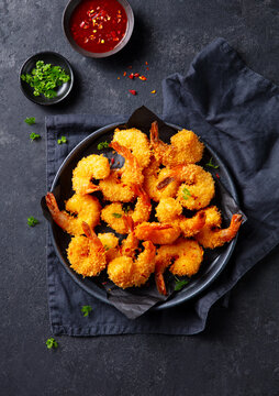 Shrimp in crunchy panko crust, spicy dipping sauce, minimalist food styling, gourmet seafood presentation. Dark grey background. Top view.