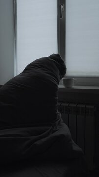 Cold home due to high energy costs, man covering himself with blanket near radiator, social problem of heating poverty and winter survival in apartment, vertical video