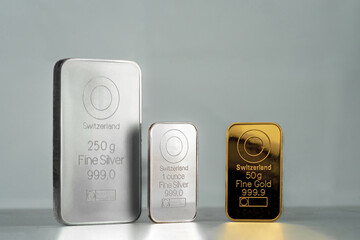 Gold and silver bullion bars of different sizes displayed on a neutral background. Concept of wealth, investment, precious metals, and financial security. Selective focus.