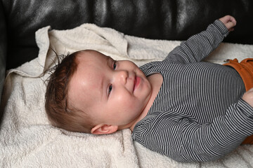 child lying on a sofa while his mother prepares him