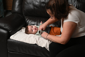child lying on a sofa while his mother prepares him