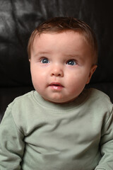 young child sitting on a black sofa