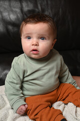 young child sitting on a black sofa