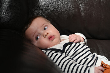 close-up of a young child wearing a sailor shirt sitting on a black sofa