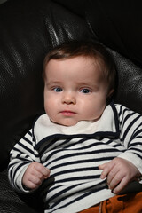 close-up of a young child wearing a sailor shirt sitting on a black sofa