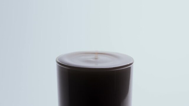 Two liquid drops fall one by one into milk in a clear glass, forming a central splash column and expanding circular ripples. Minimal clean background highlights fluid motion and surface tension.