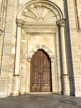 Ornate wooden double doors framed by intricate stone archway and decorative elements on a historic building exterior