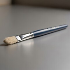Fototapeta premium Artistic blue handled paintbrush resting on grey surface close up view