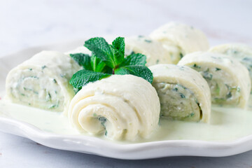 Gebjalia, a traditional Megrelian dish, cold appetizer of cheese with mint, Georgian cuisine, on a white plate, homemade.