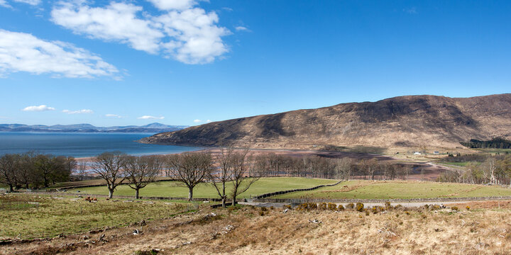 Applecross, Scotland - April 06, 2016: Panoramic view of hills, water, and trees under a clear sky