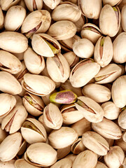 A close-up, top-down view of many shelled pistachios, with a few showing their green kernel.