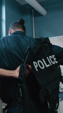 Cop putting on tactical vest in precinct office
