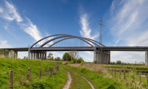 Modern highway arch bridge spanning the St&ouml;r River near Itzehoe, Schleswig-Holstein, Germany, under bright blue sky.