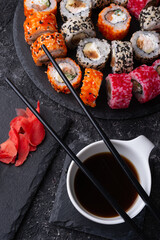 different sushi rolls set with fish beautiful served  at black dishes at black table. top view