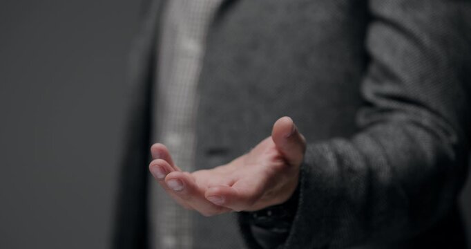 Moody close-up of a male business hand reaching out toward the viewer, representing assistance, trust, and collaboration. Unrecognizable person, soft background blur, copy space.