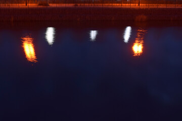Obraz premium Reflection of lights on the embankment in the water at night.