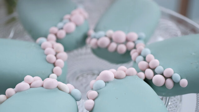 Artisan mint green cakesicles decorated with delicate pink and white sugar pearls on a glass platter